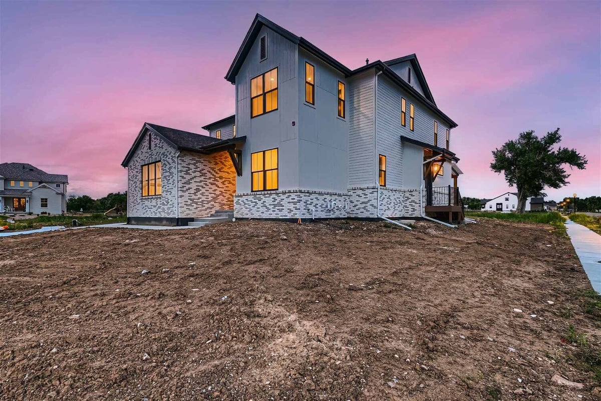 Low-angle exterior front view of a custom home with a front yard by Sheffield Homes in Westminster, CO