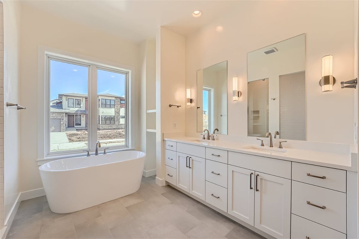 Bathroom with dual vanities, a freestanding bathtub, and a sliding window in a Sheffield Homes home in Westminster, CO