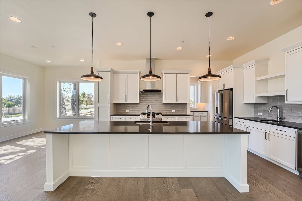 Kitchen island featuring a marble countertop with pendant lighting overhead in a home by Sheffield Homes in Westminster, CO