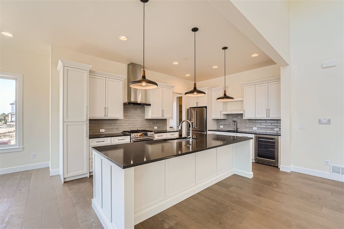 Kitchen island with a sleek countertop and pendant lighting overhead in a home by Sheffield Homes in Westminster, CO