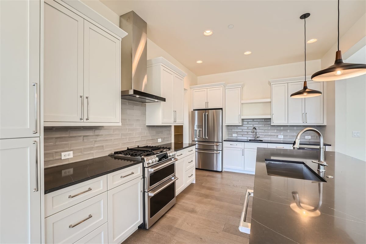 Kitchen with an island and a rear counter with stove fixtures and cabinets, by Sheffield Homes in Westminster, CO