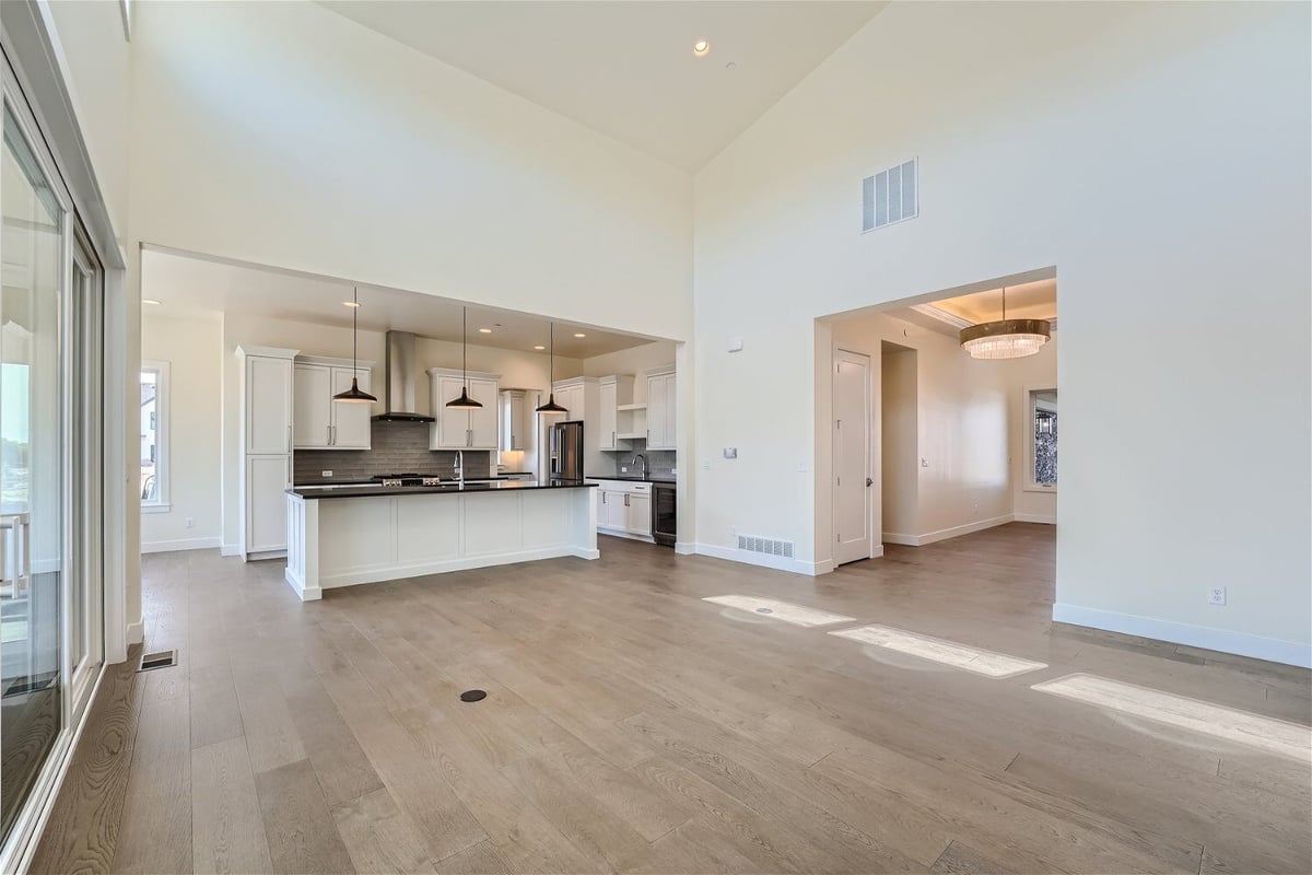 Living room featuring an open kitchen, sliding doors, and access to the dining room, by Sheffield Homes in Westminster, CO