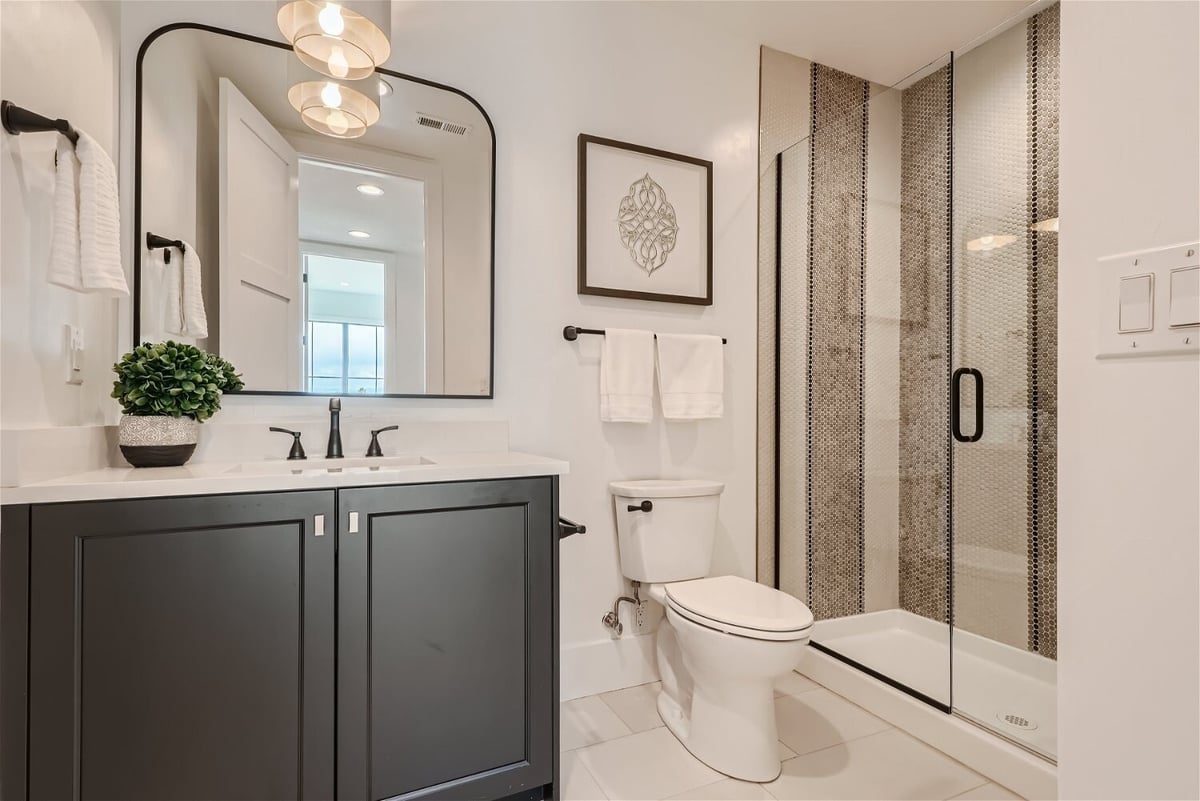 Elegant basement bathroom with glass shower and dark cabinetry, designed by Sheffield Homes in Franktown, CO