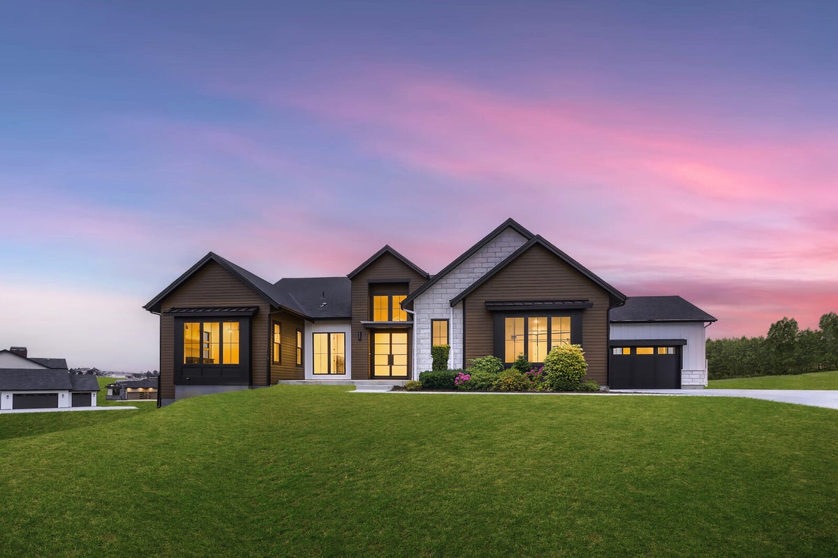 Front view of a custom-built home by Sheffield Homes in Denver, CO, showcasing a beautiful lawn and modern architectural details at sunset