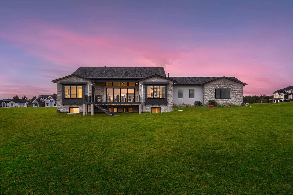 Rear view of a custom home by Sheffield Homes in Denver, CO, featuring a spacious backyard and sunset-lit windows